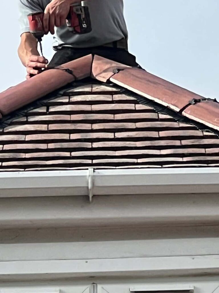 This is a photo of one of the operatives of Lingfield Roofing Repairs installing new ridge tiles