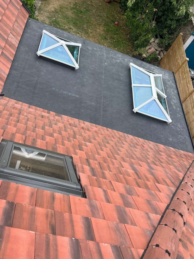 This is a photo taken from the roof ridge looking down a tiled pitched roof on to a flat roof. Works carried out by Lingfield Roofing Repairs